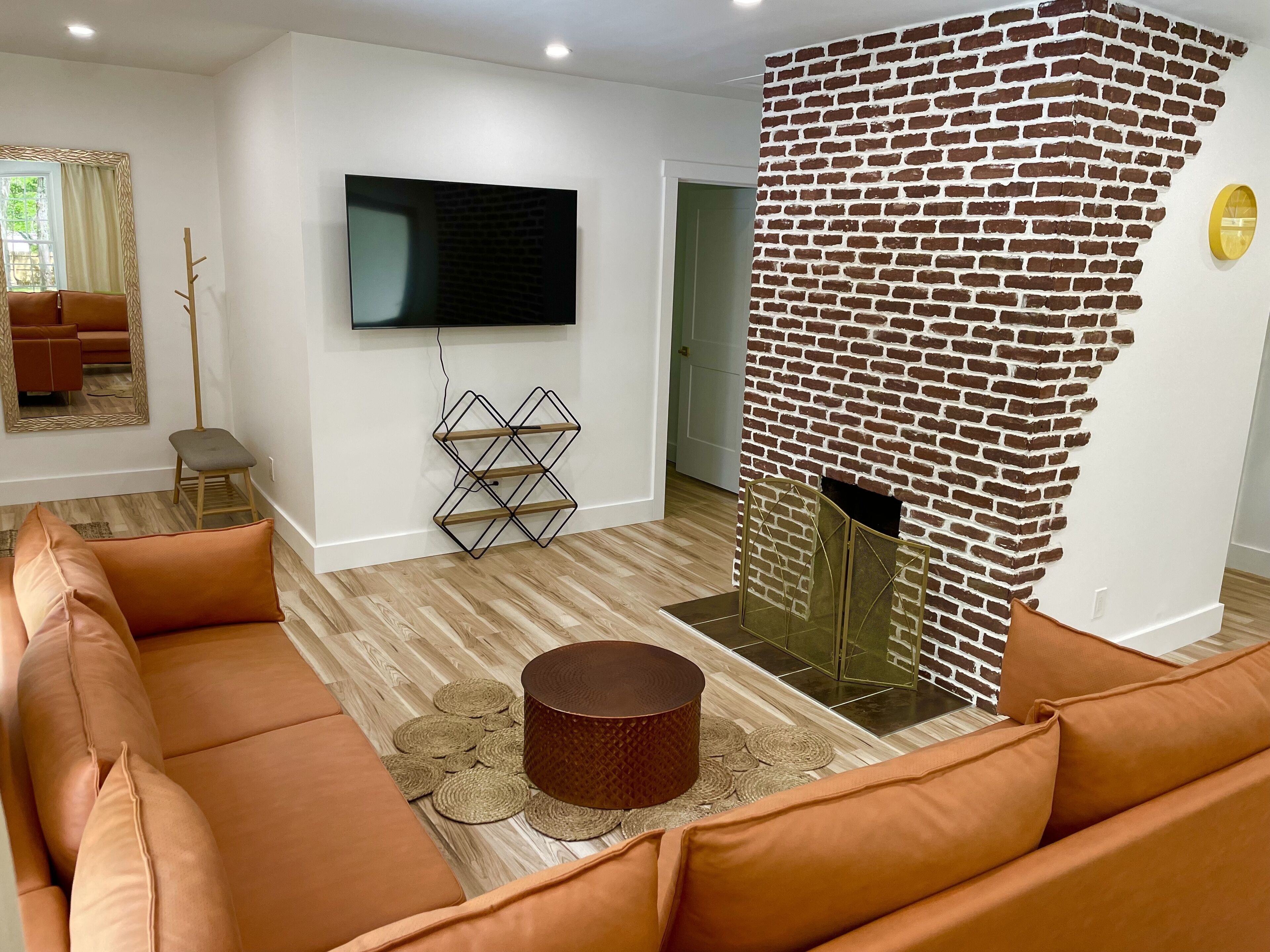 Ein Wohnzimmer mit Backsteinwand, einem flachbildfernseher an der Wand, einer Couch und einem Couchtisch.