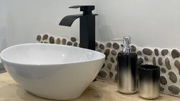 A bathroom with a white sink, black faucet, and two metallic containers on the counter.