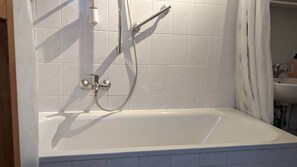 Bañera con ducha, secador de pelo, toallas, papel higiénico