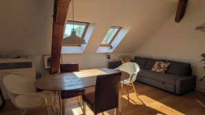 A cozy loft-style room with a dining table, chairs, a sofa, and a ceiling skylight. - Vacation apartment in a cozy farmhouse by the bathing lake with large garden and sauna (Carpin)