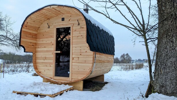 A wooden cabin with a curved roof, a door, and a chimney. - Vacation apartment in a cozy farmhouse by the bathing lake with large garden and sauna (Carpin)