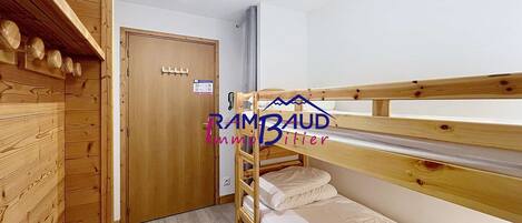 A bunk bed room with wooden walls, a door, and a ceiling light fixture.