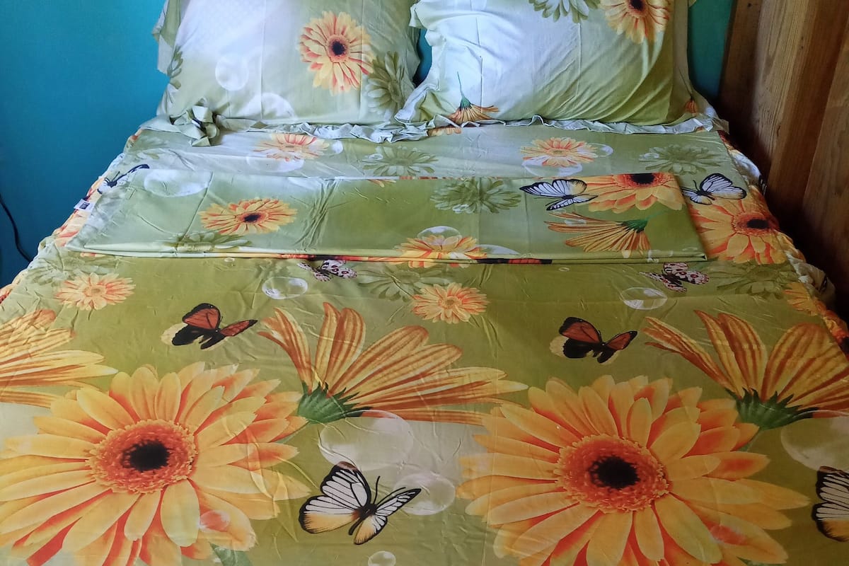 Ein Bett mit blumigem Bettbezug und Schmetterlingsmotiven.