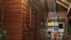 A wooden cabin with a kitchen area, a green mat with a blue logo, and a hanging rope. - Berkey's Jungle Paradise (Roseau)