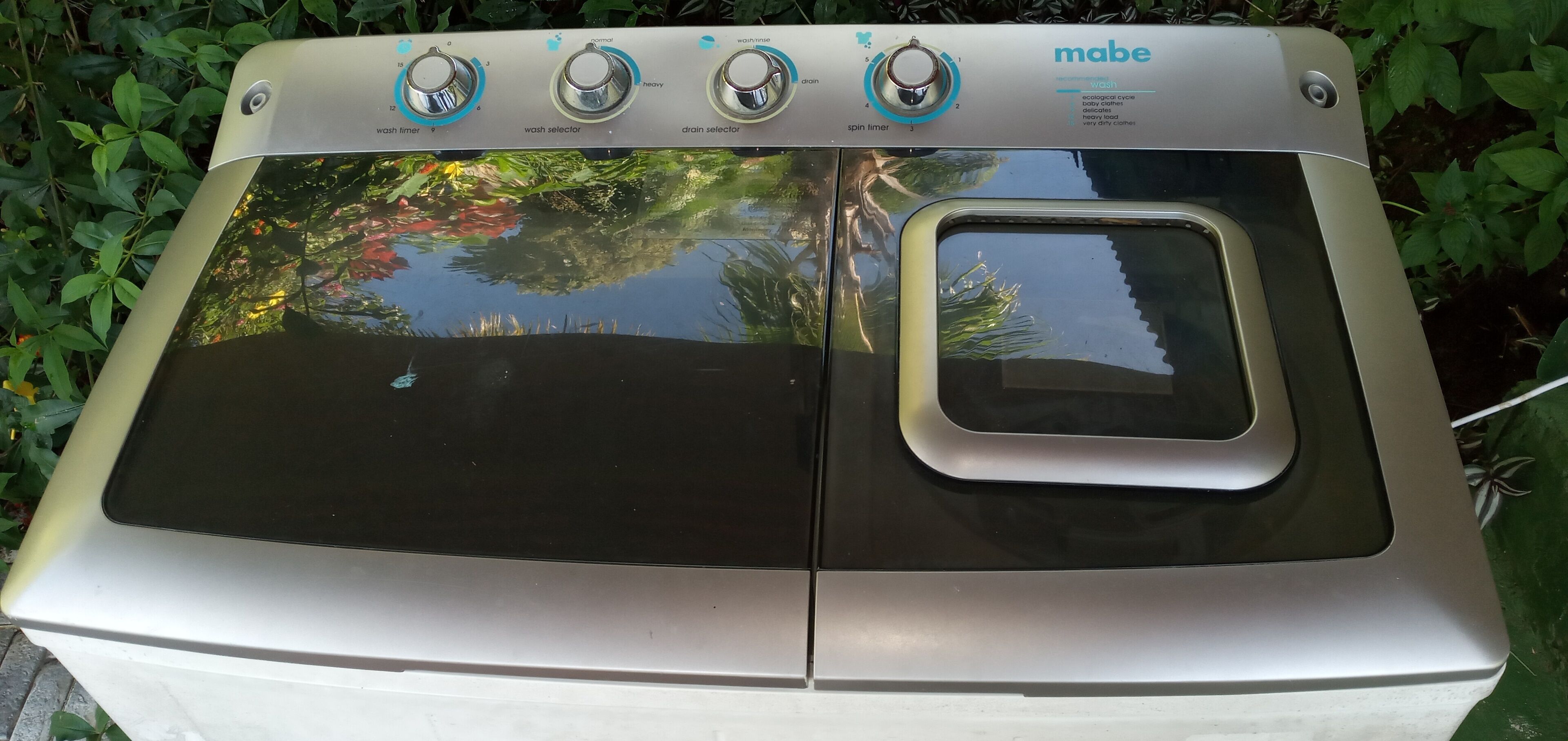 Vista frontal de una lavadora con perillas de control y un conducto de entrada de agua.