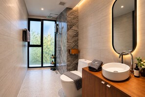 A modern bathroom with a large mirror, a round sink, and a shower area.