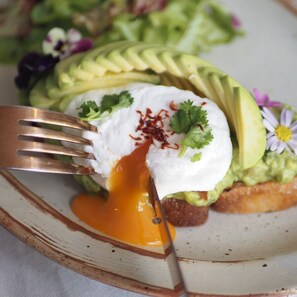 Ein Teller mit Avocado, pochiertem Ei und Koriander auf Toast.