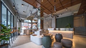 Un interior moderno con un mostrador de recepción que dice 'GOOSE Living', zonas de estar y ventanas amplias.