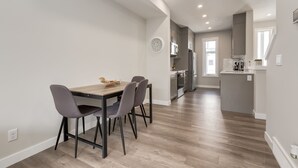 A modern kitchen with grey cabinets, a wooden dining table, and a built-in microwave. - *MODERN* 2BDRM Close to Airport & Major Highway (Calgary)