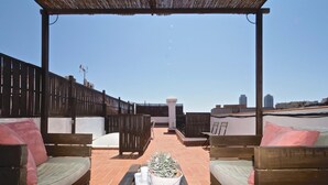 Eine Dachterrasse mit Holzmöbeln, einer Pergola und Blick auf die Skyline der Stadt.