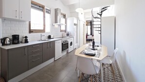 Eine moderne Küche mit grauen Schränken, einem eingebauten Backofen und einer Essecke mit Tisch und Stühlen.
