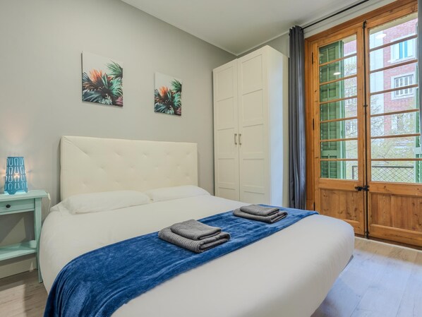 A bedroom with a bed, a wardrobe, a nightstand, and a window with curtains.