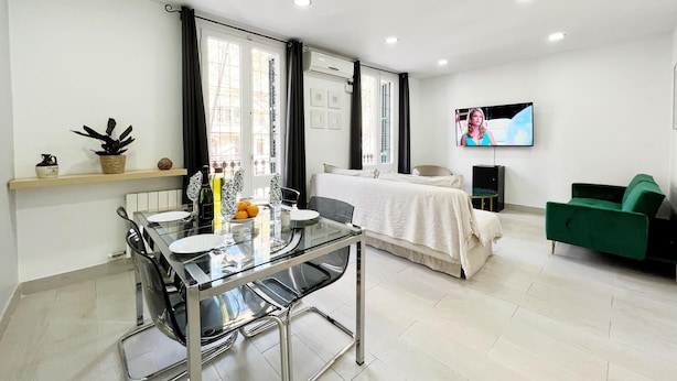 Una sala de estar moderna con una mesa de comedor de vidrio, un sofá y un televisor montado en la pared.