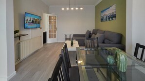 A modern living room with a glass dining table, grey sofa, and a painting on the wall. - Sagrada Familia Penthouse (Barcelona)