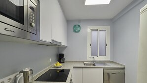 A compact kitchen with a microwave, kettle, coffee maker, sink, and dishwasher. - Sagrada Familia Penthouse (Barcelona)