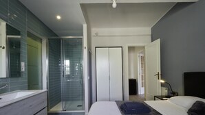 A modern bedroom with a large bed, a walk-in closet, and a glass-enclosed shower. - Sagrada Familia Penthouse (Barcelona)