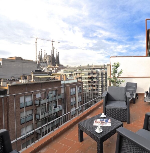 Une terrasse sur le toit avec des sièges en plein air, une vue sur le paysage urbain et une grue de construction en arrière-plan.