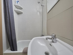 A bathroom with a white sink, a shower, and a towel rack. - Gran Via Terrace Barcelona (Barcelona)