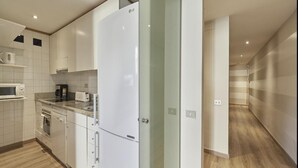 Eine moderne Küche mit weißen Schränken, einem eingebauten Mikrowellenherd, einem Toaster und einem Kühlschrank.
