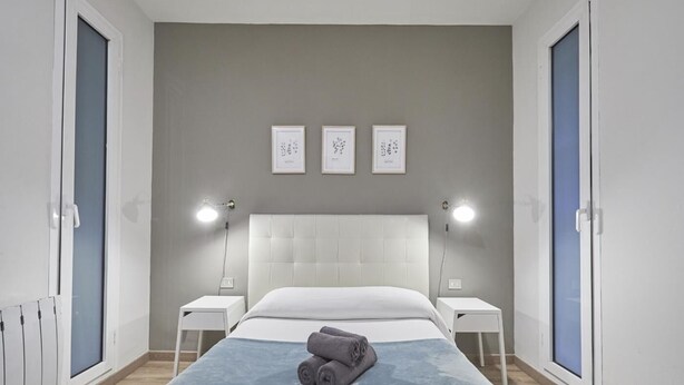 Ein Schlafzimmer mit einem großen Bett, zwei Nachttischen, einem Kopfteil und drei gerahmten Bildern an der Wand.
