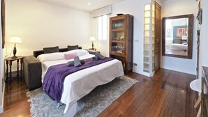 Ein Hotelzimmer mit einem Bett, einem Holzschrank, einem Spiegel und einem kleinen Tisch mit einer Lampe.