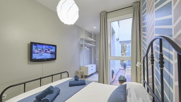 Ein Hotelzimmer mit Bett, Fernseher, Fenster und Balkon.