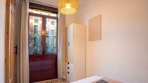 Ein Hotelzimmer mit Bett, Schrank, einer Tür zu einem Außenbereich und einer Pendelleuchte.