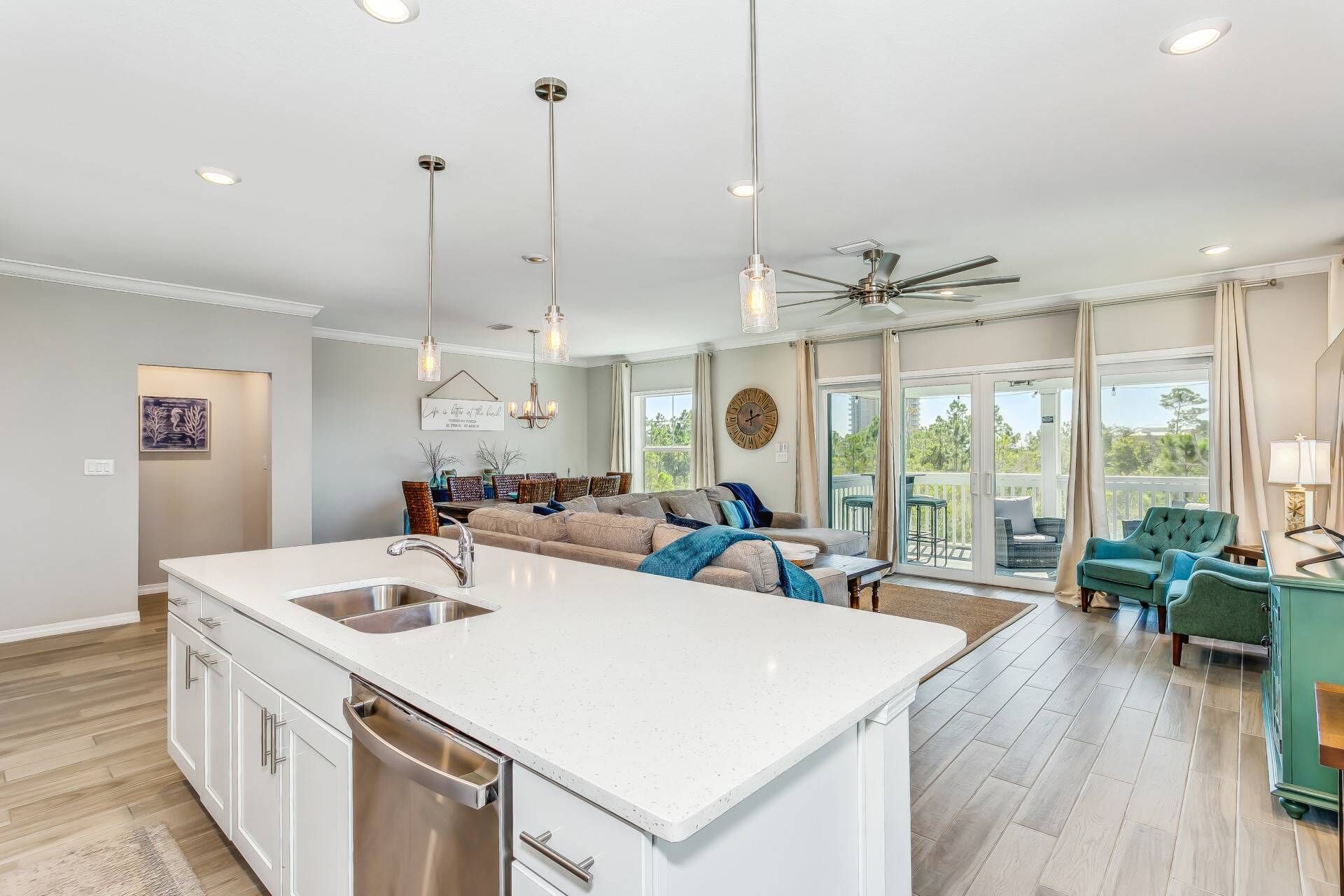 A spacious kitchen with a central island, a dining area with a sofa, and a view of the outdoors through large sliding doors.