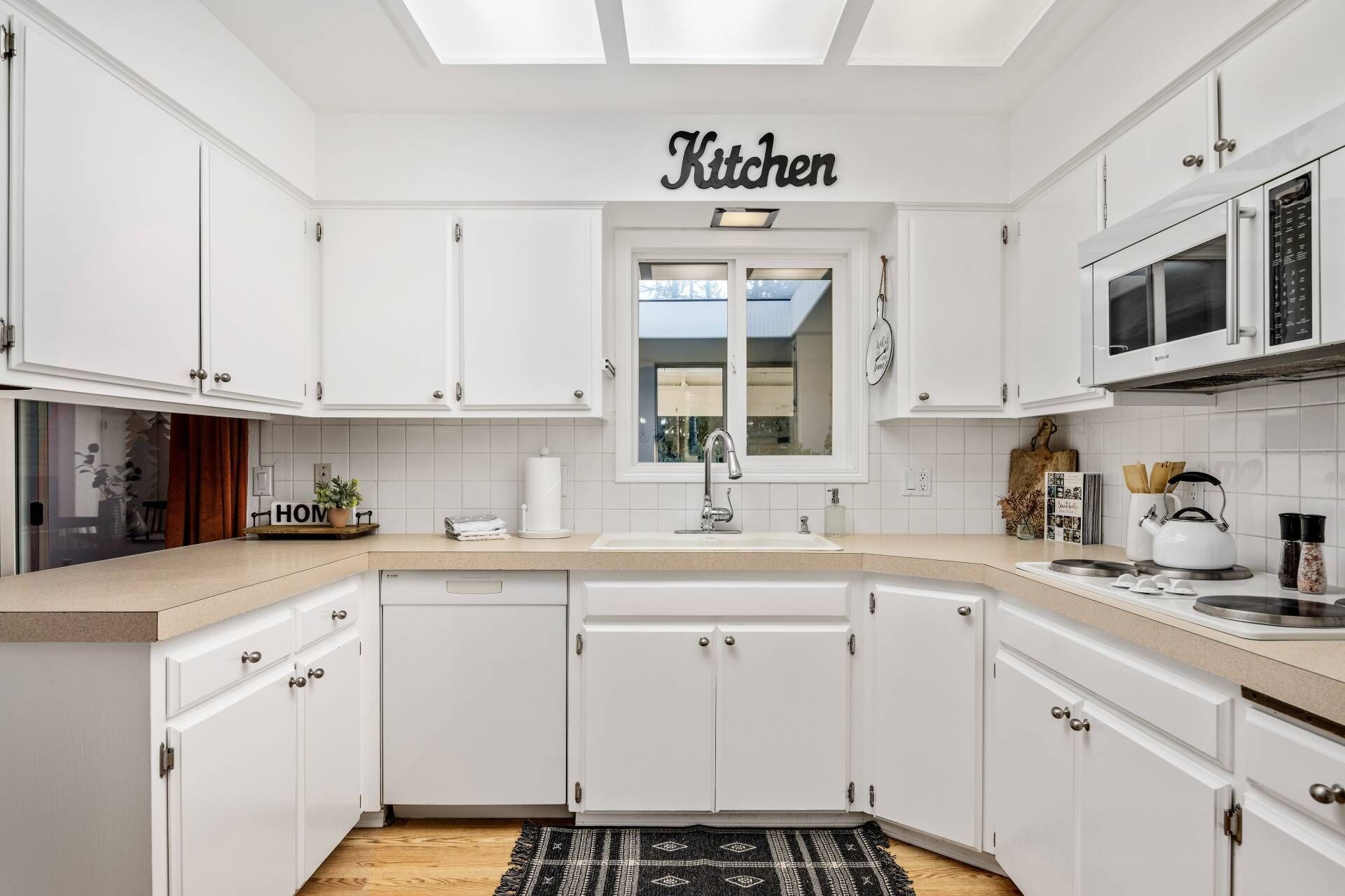 A modern kitchen with white cabinetry, a central island, and a microwave.