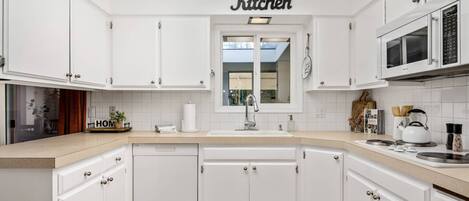 A modern kitchen with white cabinetry, a central island, and a microwave.
