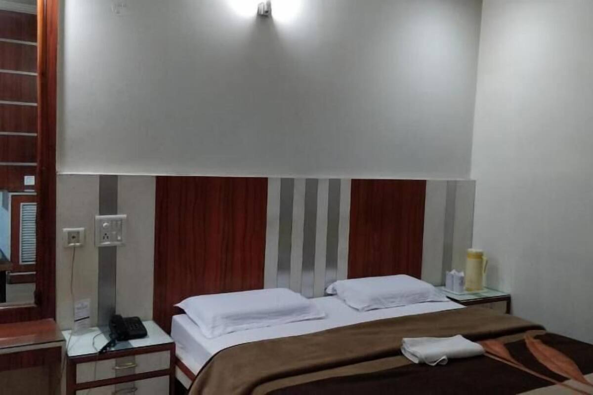 A hotel room with a bed, bedside tables, a mirror, and a wall-mounted light fixture.