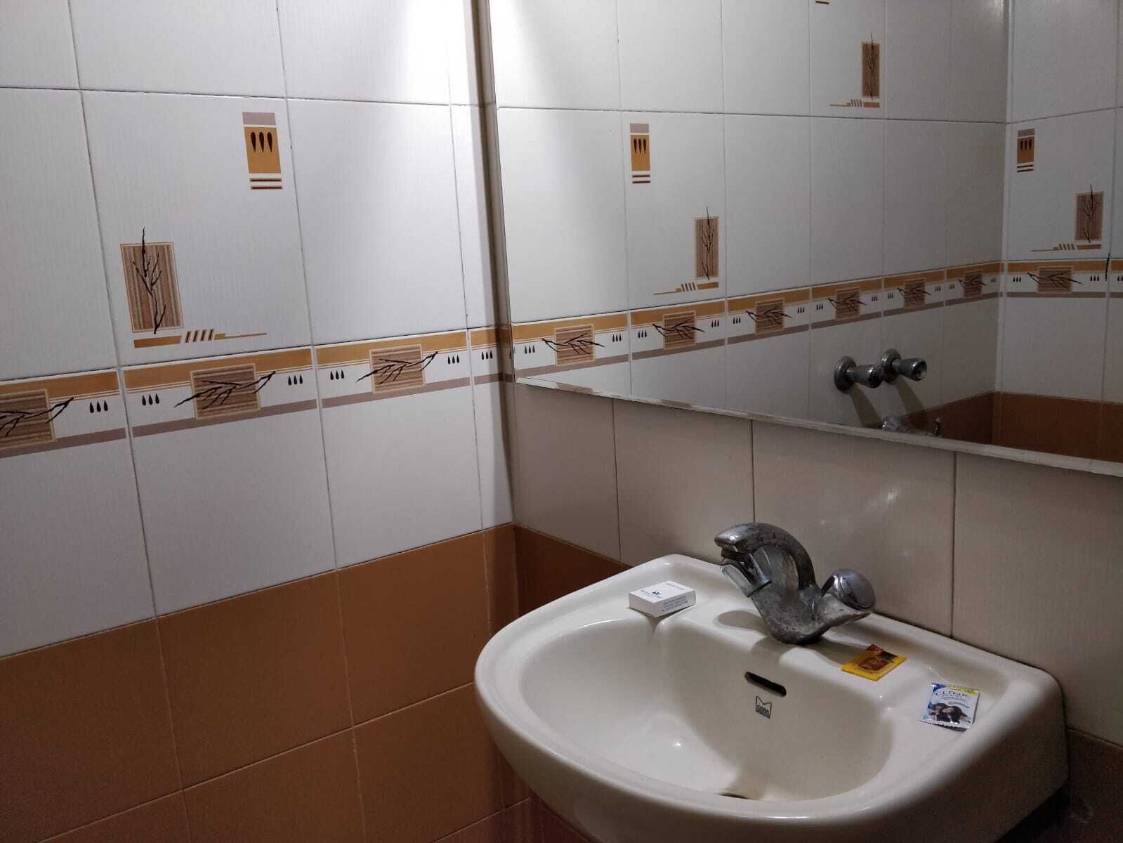 A bathroom with a sink, mirror, and patterned tiles.