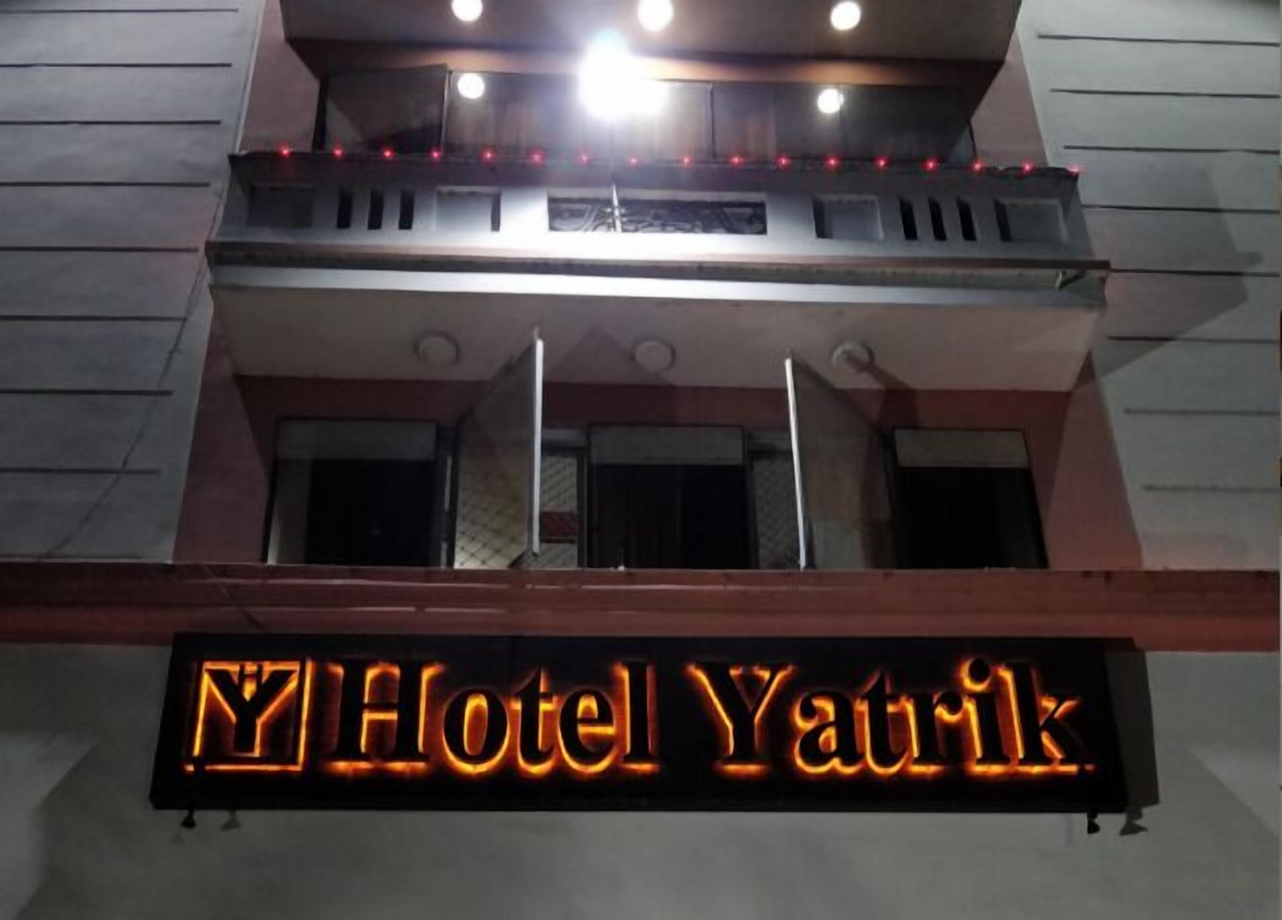 Un letrero de hotel con el nombre 'Hotel Yanik' iluminado en naranja.