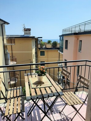 Enjoy the ocean view from this balcony with a table and chairs, surrounded by a potted plant.