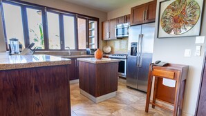 A kitchen with dark wood cabinets, a granite countertop, a stainless steel refrigerator, and a microwave. - Sweeping Banderas Bay Views, Rooftop Pool & Bar - Residences by Pinnacle Unit 20 (Puerto Vallarta)