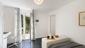 Un dormitorio moderno con un escritorio, una banca acolchada y vistas al verdor exterior.