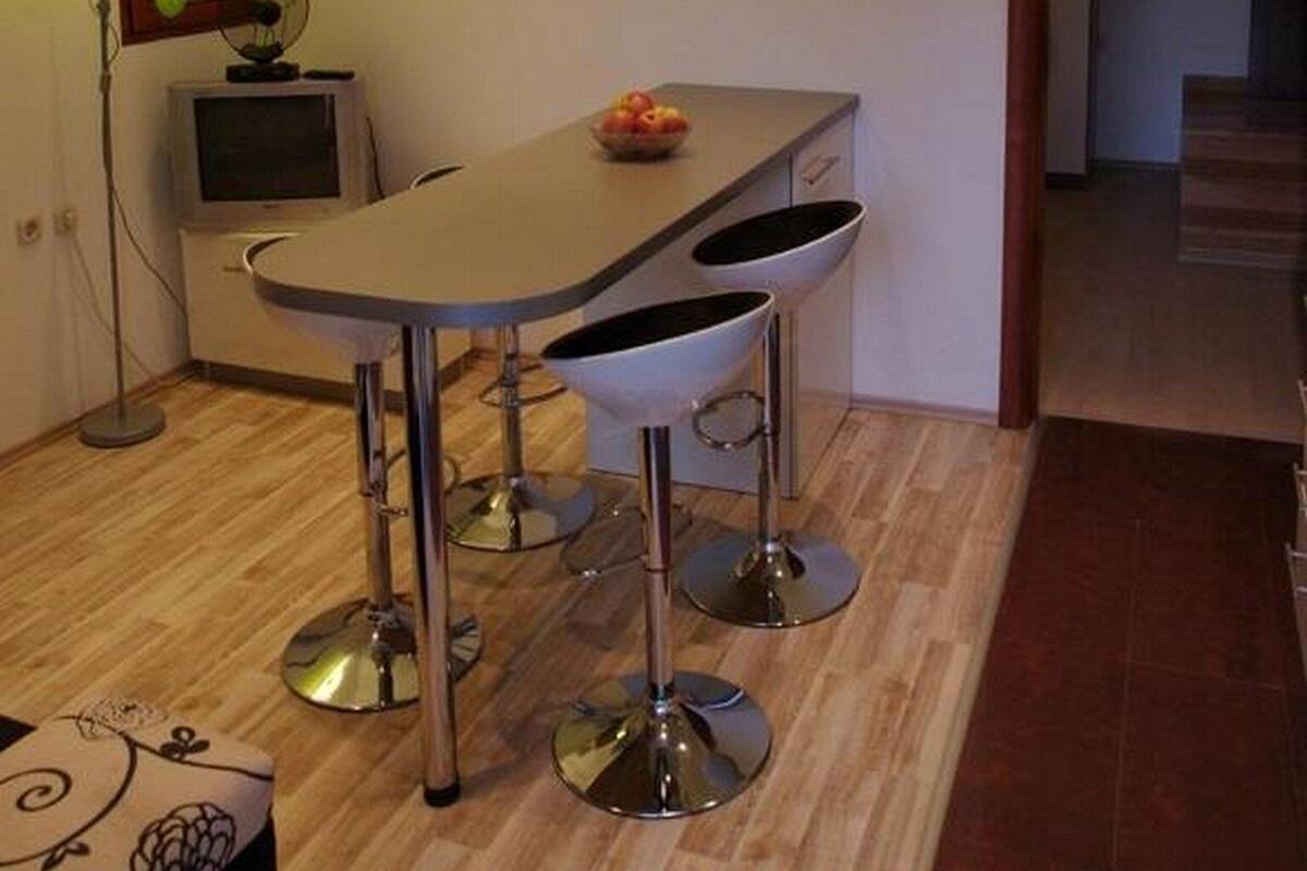 Una cocina moderna con una encimera curva, un bol de fruta y un televisor antiguo.