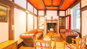 A traditional living room with a fireplace, leather sofas, and striped chairs.