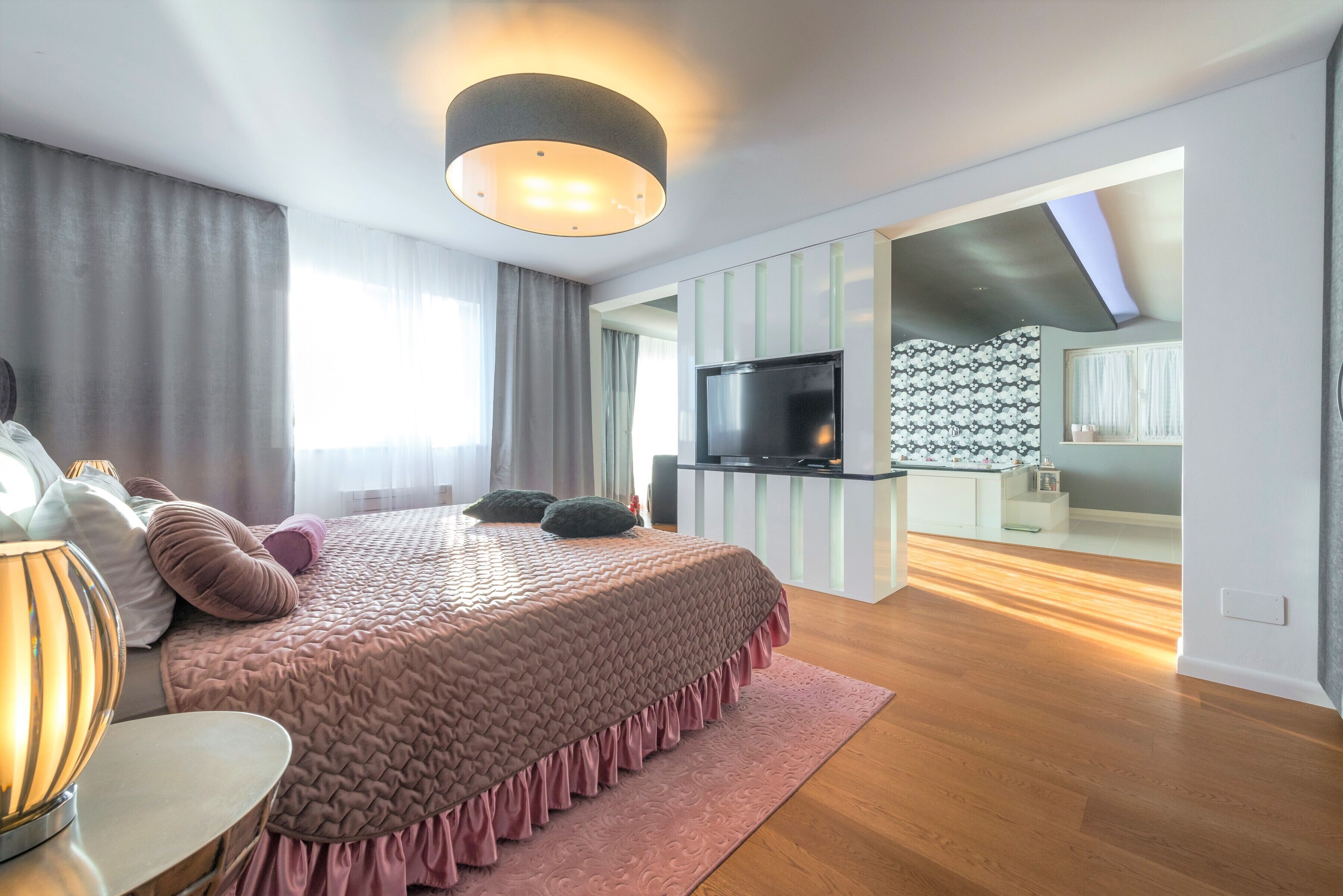 Een moderne slaapkamer met een groot bed, een televisie en een nachtkastje.