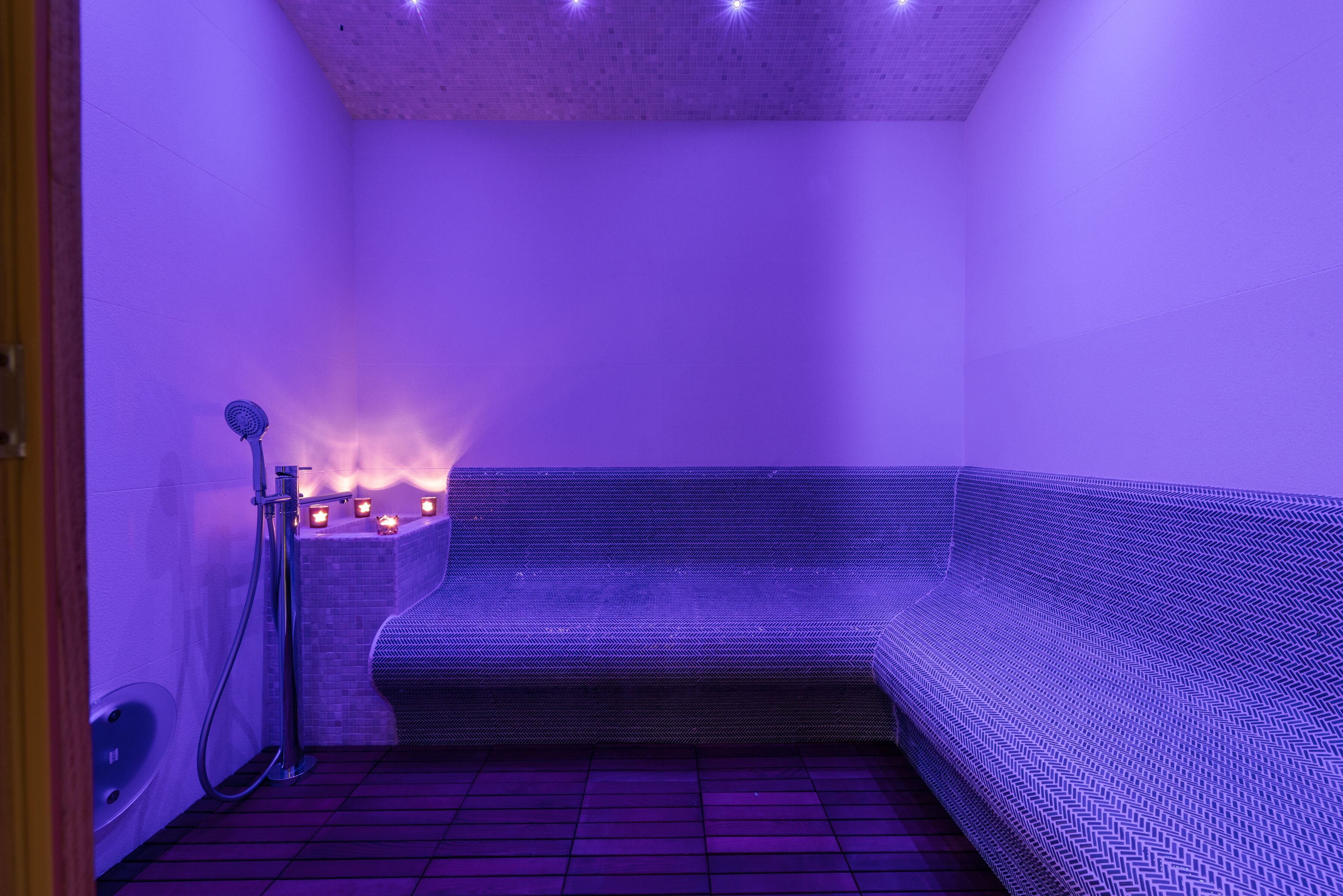 A modern spa room with a heated floor, a seating area, and a small fire feature.