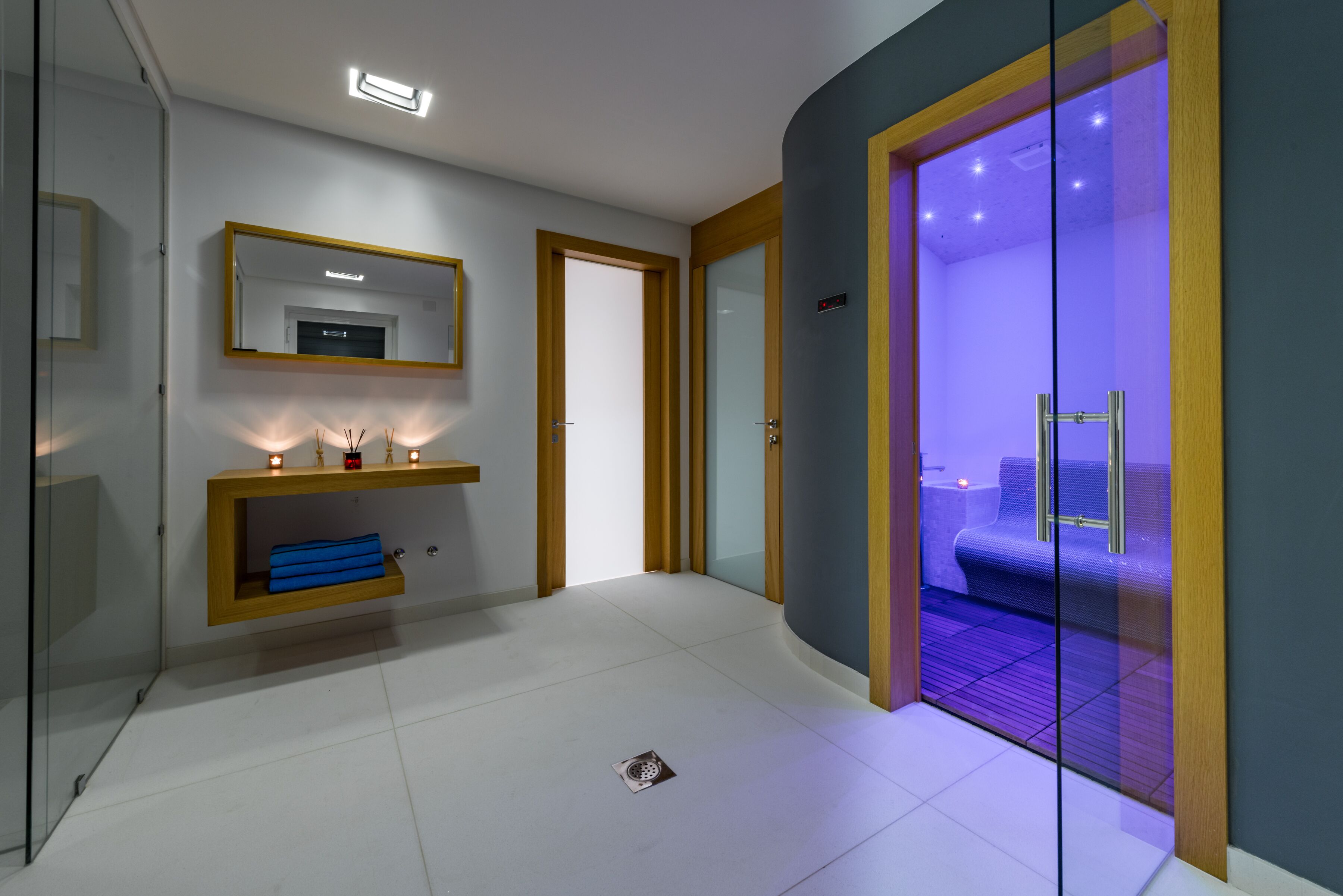 A modern bathroom with a glass shower enclosure, a vanity with a mirror, and a blue towel on the shelf.