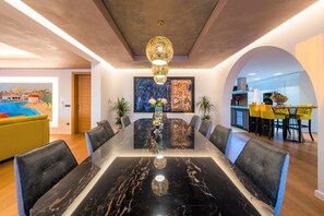 A modern dining area with a marble table, black chairs, and a unique chandelier.