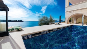 Piscina con vista despejada al mar y a la costa lejana.