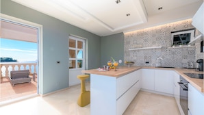 Una cocina moderna con una isla central, armarios blancos y salpicadero con diseño.