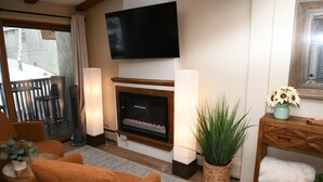 Ein Wohnzimmer mit Kamin, Flachbildfernseher, einer Couch und einem Essbereich mit Stühlen.