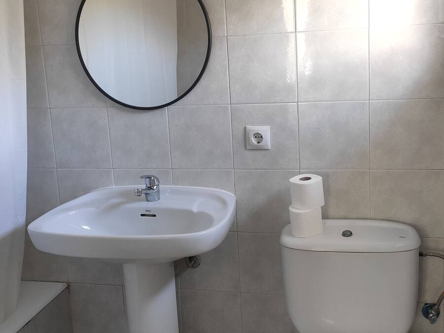 A bathroom with a white sink, a toilet, and a wall-mounted mirror.