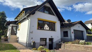 Ein zweistöckiges Haus mit einem steilen Dach, einer Satellitenschüssel und einer Garage.
