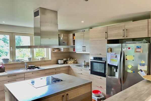 A modern kitchen with a central island, stainless steel appliances, and wooden cabinetry.