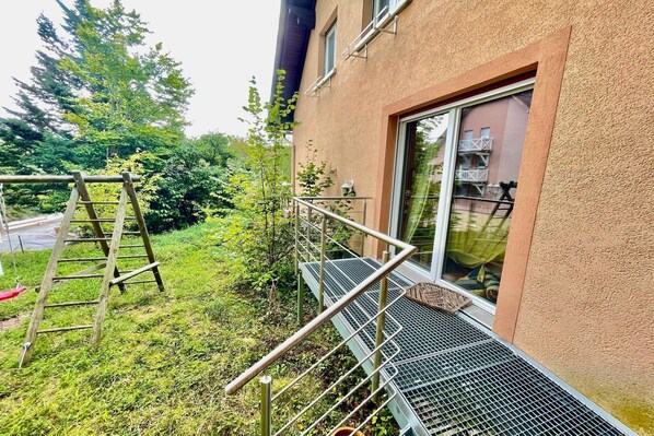 A building with a metal staircase leading to a window, surrounded by greenery.