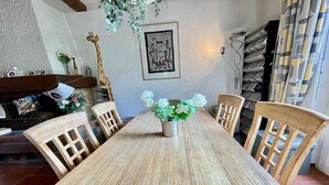 En matplats med ett träbord och stolar, en vas med blommor och en giraffdekoration på väggen.